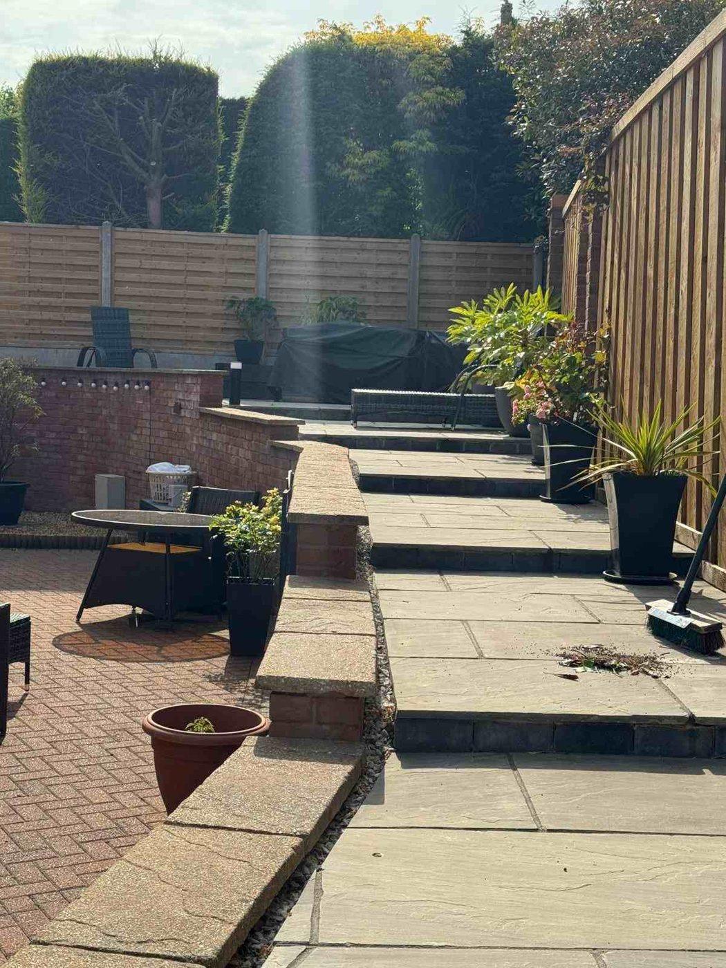 Grey sandstone steps and tiers running up the side of the garden in Bramshall, beside the brick retaining wall