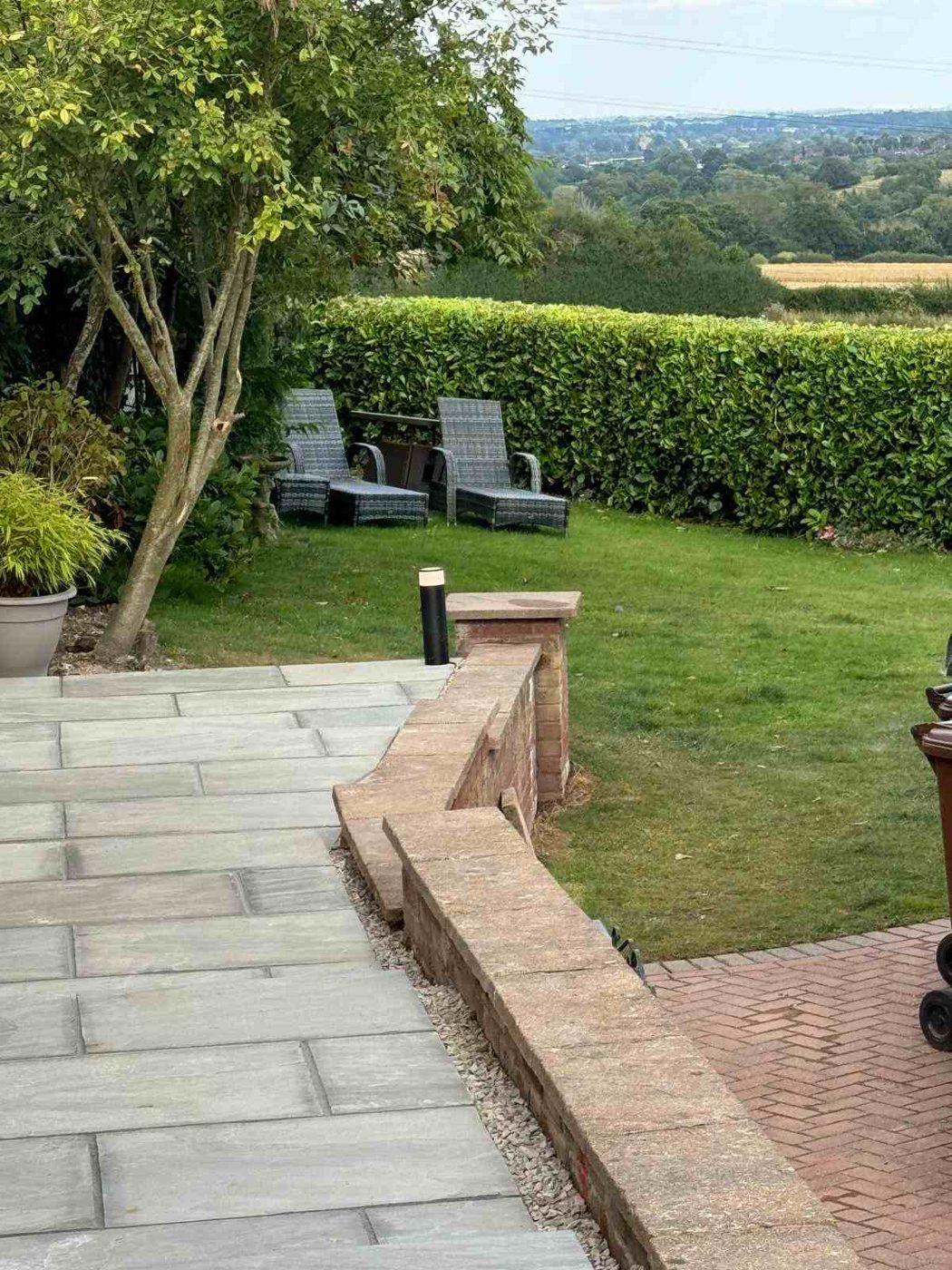 Sandstone patio beside the brick retaining wall, looking out over the lawn and countryside in Bramshall