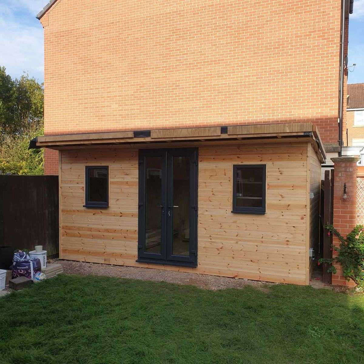 Timber-clad garden building with anthracite French doors and windows, built by DOT Services at the bottom of a garden